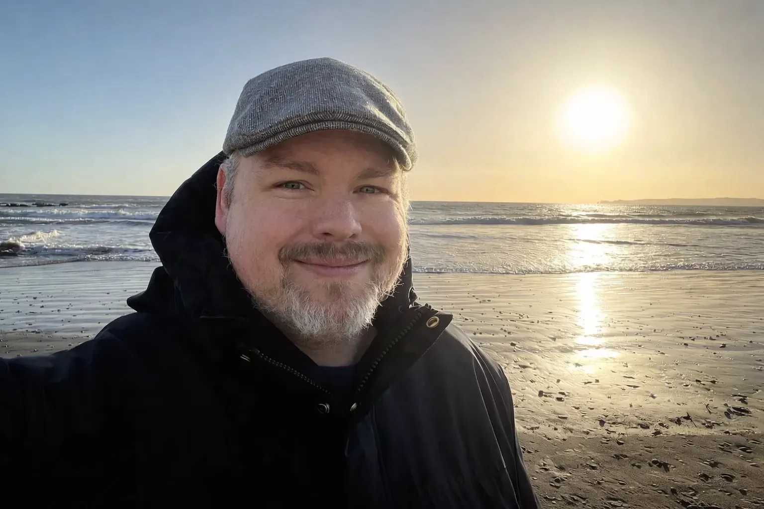 Peter Elst smiling on a beach at sunset.